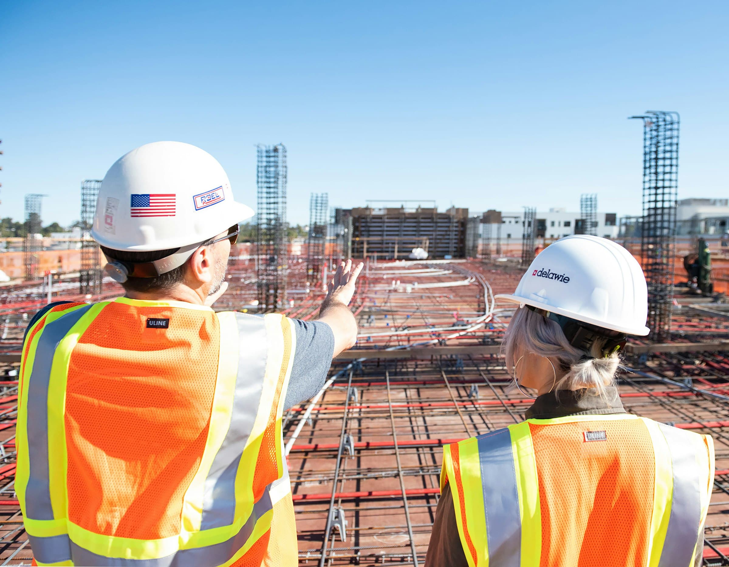 Two site leads in hard hats reviewing a rebar deck