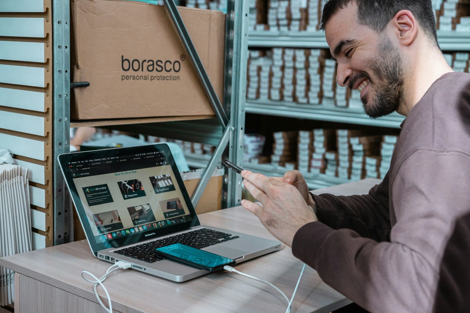 Warehouse employee checking an order on a laptop and phone
